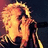 Pixelated image of a person with light hair singing into a microphone, red text labels, and a heart symbol on a dark background.