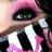 Pixelated close-up of a character with green eyes, pink hair, and white-and-black clothing against a dark background.