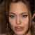 Pixelated close-up of a person's face with brown hair, visible eyes, nose, mouth, and light skin tone against a dark background.