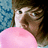 Pixelated close-up of a person with brown hair wearing a pink top against a blue and dark background.