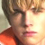 Pixelated close-up of a person's face with light brown hair and an orange top, displayed as a static buddy icon.
