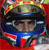 Pixelated image of a person wearing a dark helmet with blue accents and a blue scarf, set against a red background with yellow and green highlights.