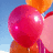 A cluster of colorful balloons against a blue sky background with subtle cloud details.