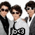 Three pixelated figures in formal attire with dark hair and sunglasses, one holding a microphone labeled 'ib3' against a white background.