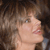 Pixelated close-up of a person's face with light skin tone, brown hair, and visible facial features including eyes, nose, lips, and chin against a dark background.