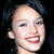 Pixelated close-up of a person's face with dark hair, showing a smiling expression and visible teeth against a dark background.