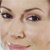 A close-up of a person's face showing eyes, eyebrows, nose, and mouth with a slight smile, rendered in pixelated style.