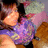 Pixelated static image of a figure with orange-toned hair, purple clothing, and a pinkish background with green and brown elements.