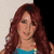 A person with long red hair wears a blue sleeveless top and white pants, holding yellow objects against a light background.