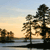 Pixelated landscape with trees and water under a gradient sky transitioning from light blue to warm orange.
