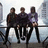 Three people sit on a railing against a cityscape background with blue text reading 'I LOVE THE KLAXONS BEST BAND EVER!!!'