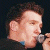 A 50x50 pixel animated contact sheet showing two frames of a person singing into a microphone on the left and green text reading "Original Icons .com" on the right against a dark background.