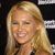 Pixelated close-up of a smiling person with long blonde hair against a dark background with white horizontal lines.