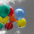 Colorful circular shapes in green, red, yellow, and blue float against a gray background with subtle white highlights.