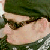 A close-up of a person's face with dark hair and sunglasses, set against a green background with white accents.