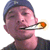 A person wearing a blue cap and dark shirt holds a cigarette with an orange tip, exhaling smoke in four