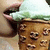 A person's mouth and nose hold a light green-topped ice cream cone with brown waffle texture, showing slight movement in the lower-left