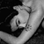 A grayscale pixelated image shows a hand holding a small object against a dark background with light gradient.