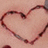 A heart-shaped outline drawn on skin with a dark marker, accompanied by red pixelated text on black background.