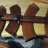 Pixelated image of two dark brown rifles with metallic parts resting on a light-colored surface against a muted background.