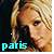 Pixelated close-up of a person with light brown hair and fair skin, wearing a dark top, with the word 'paris' in cyan text at the bottom left.