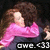 Pixelated image of a person with brown hair wearing pink long sleeves and dark pants, holding an object near their face against a black background.