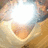 A pixelated circular icon with a bright white center surrounded by a gradient of light brown and beige tones, forming a soft, glowing effect.