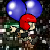 Pixelated character with red helmet holds green object while two blue balloons float above against dark background