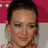 Static pixelated image of a person with dark hair against a red and white background, showing partial facial features and a neutral expression.