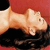 A pixelated figure in a reclined pose with light skin tones against a red and black background.