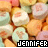 A pixelated image of pastel-colored candy hearts with the name 'JENNIFER' displayed in block letters at the bottom, one version showing white text on black and the other pink text on black.