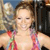 A pixelated image shows a person in a colorful bikini top holding a large silver object, with a dark structure and blue sky in the background.