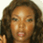 Pixelated close-up of a person with dark curly hair, light brown skin, and closed eyes, mouth slightly open, against a light background.