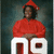 A person in a red graduation cap and gown sits behind large white '2009' numerals on a dark background.
