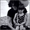 Black-and-white animated sequence showing a person with long hair and tattoos holding a child in polka-dot dress, transitioning through poses including text overlays.