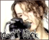 A person with curly brown hair holds a black camera near their face, with text reading 'don't blink' below the image.