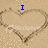 Pixelated beach scene with two heart-shaped sand drawings and blue text reading "I wish I could be with you now" on a light brown background.