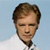 Pixelated portrait of a person with brown hair and closed eyes against a light blue background, wearing a white collared shirt.