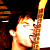 Pixelated static image of a person holding a glowing yellow object against dark background with partial white area on right.