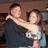 A pixelated image shows two people embracing, with a woman in a silver dress and man in dark clothing against a brown background.