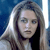 Pixelated close-up of a person with long light brown hair against a blue background, wearing a dark top.