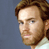 Pixelated static image of a person's face with brown hair and beard against a blue background, rendered in low-resolution 256x256 pixels.