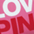 A static image of stylized text with pink and red hues, featuring a large white circular shape containing a smaller pink circle.