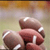 Pixelated static image of a hand holding two footballs against a blurred background with warm tones.