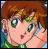 Pixelated close-up of a character with light skin, large green eyes, and brown hair, wearing a green garment against a blurred background.