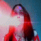 showing a person with long red hair and red clothing against a blue background, with bright light effects across the face