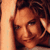 Static pixelated image of a person's face with brown hair and warm-toned skin, cropped closely on the right side against an orange background.