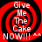 Red and black spiral background with white text "Give Me The Cake NOW!!!" and two small white asterisks.