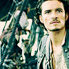 Two people with long hair appear in a low-resolution static image; one person has a mustache and wears a dark jacket over a light shirt.