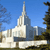 A pixelated image of a white building with a tall spire against a blue sky, flanked by trees and other structures.